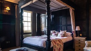 A four-poster canopy bed with a nightstand and a chair, a window with curtains, and a lamp on the nightstand. - Mosborough Hall Hotel, BW Signature Collection (Sheffield)