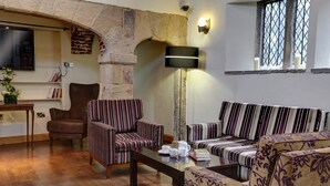 A cozy living room with striped sofas, a coffee table, and a stone archway. - Mosborough Hall Hotel, BW Signature Collection (Sheffield)