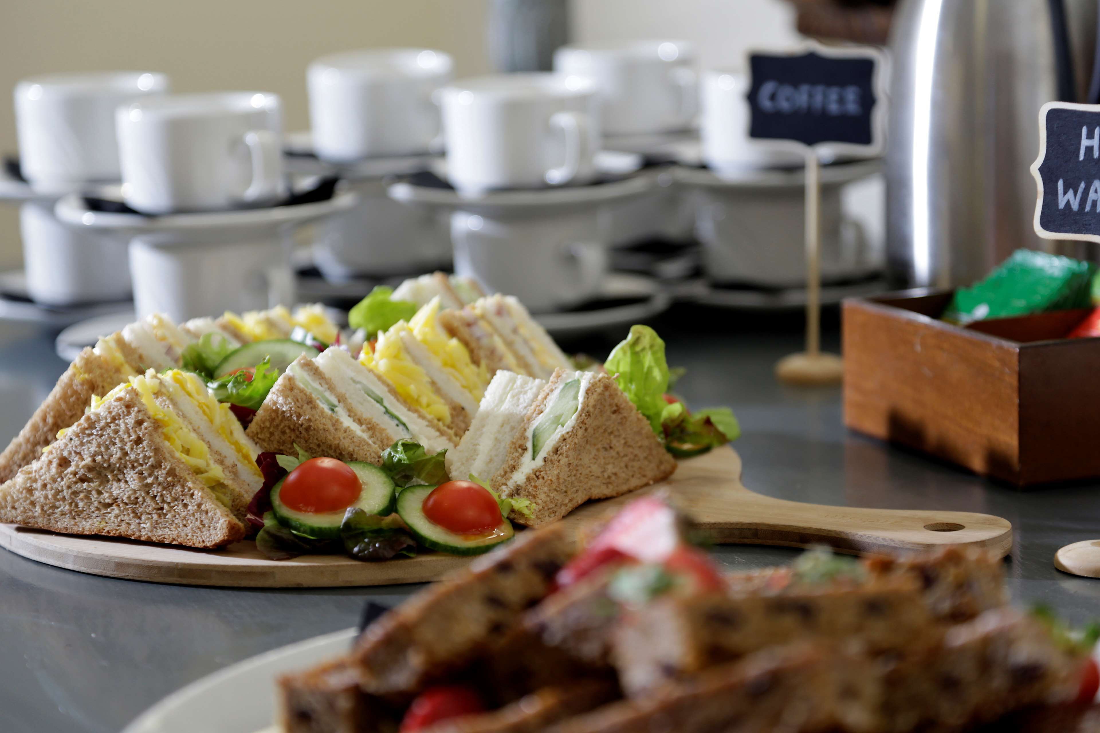 A table with sandwiches, salad, and a coffee station.