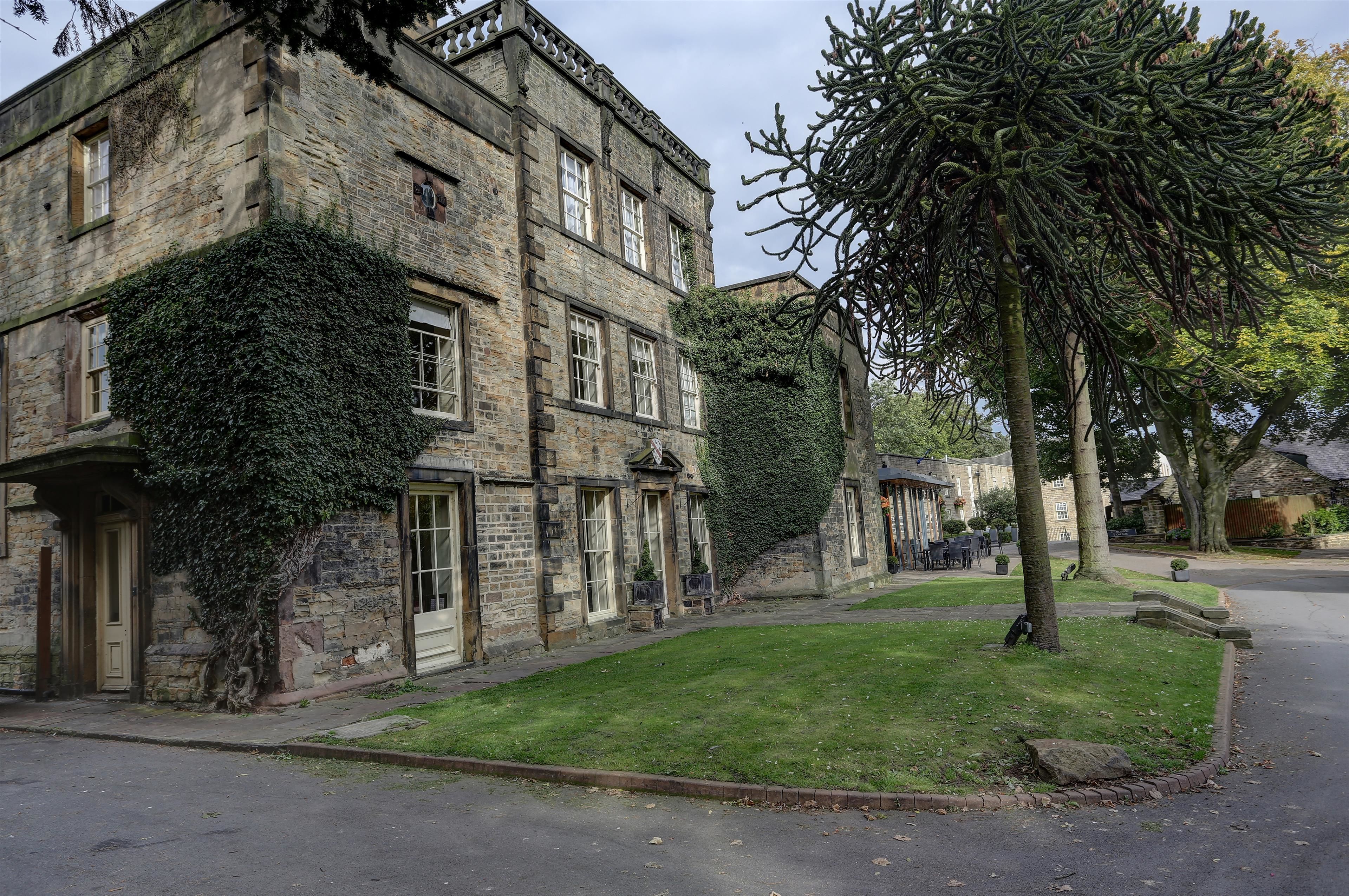 A historic stone building with ivy-covered walls and a well-maintained lawn.