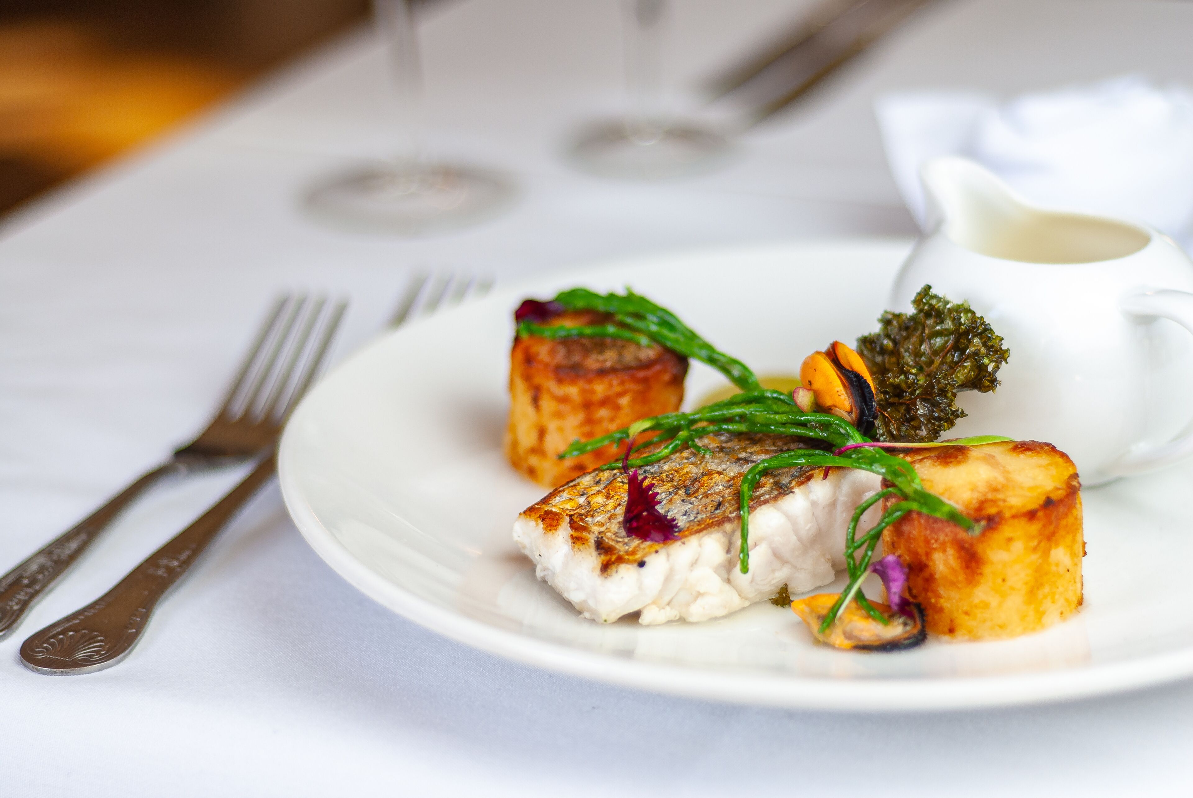A plate of food with a fork and knife on a white tablecloth.