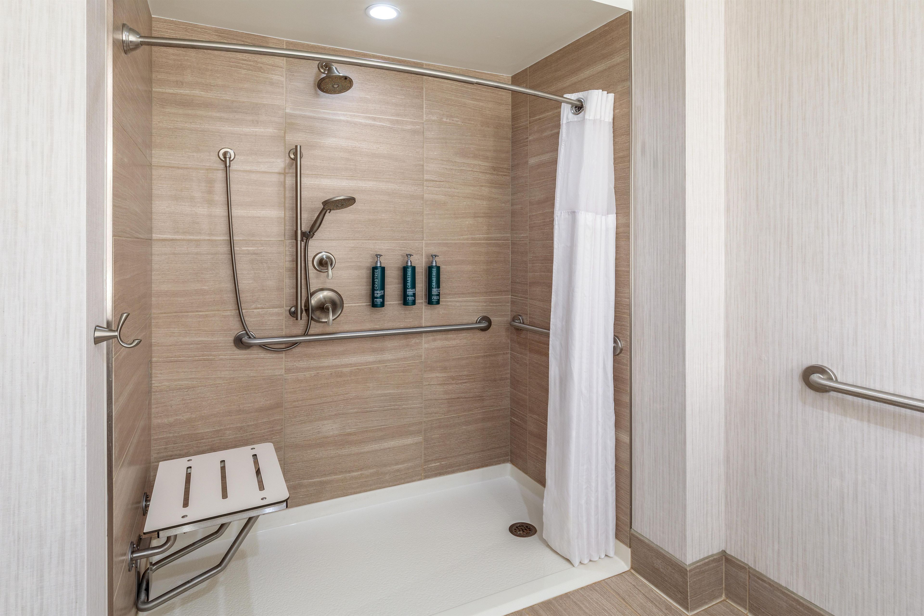 Un espace douche équipé d’une barre d’appui, d’un pommeau de douche à main et d’un robinet à main.