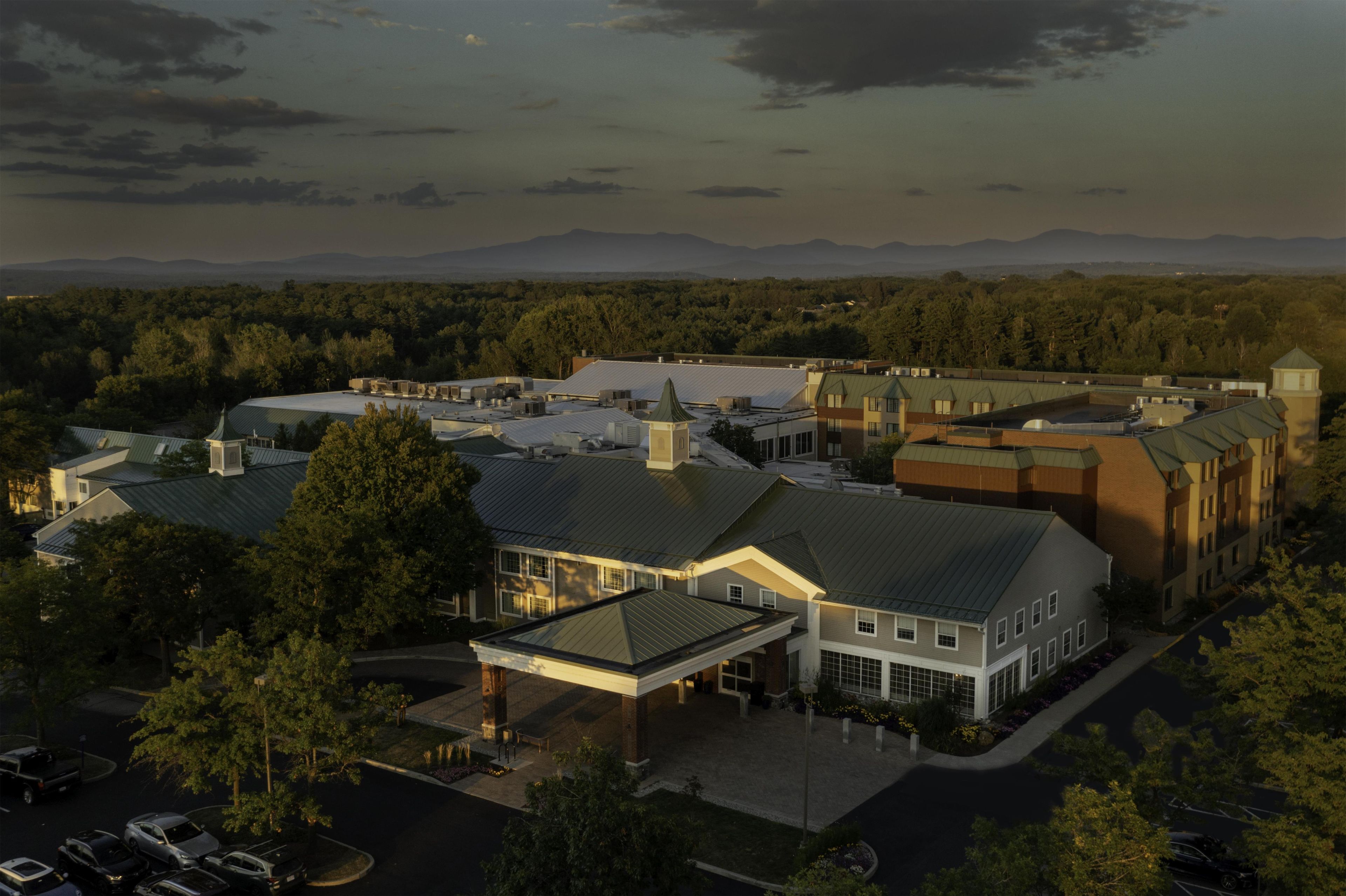 A large building complex with multiple roofs and a parking area.