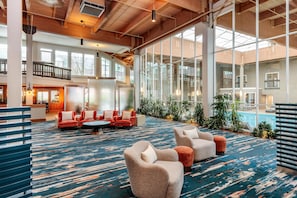 A spacious lobby with a large seating area, a pool, and a view of the building's interior.