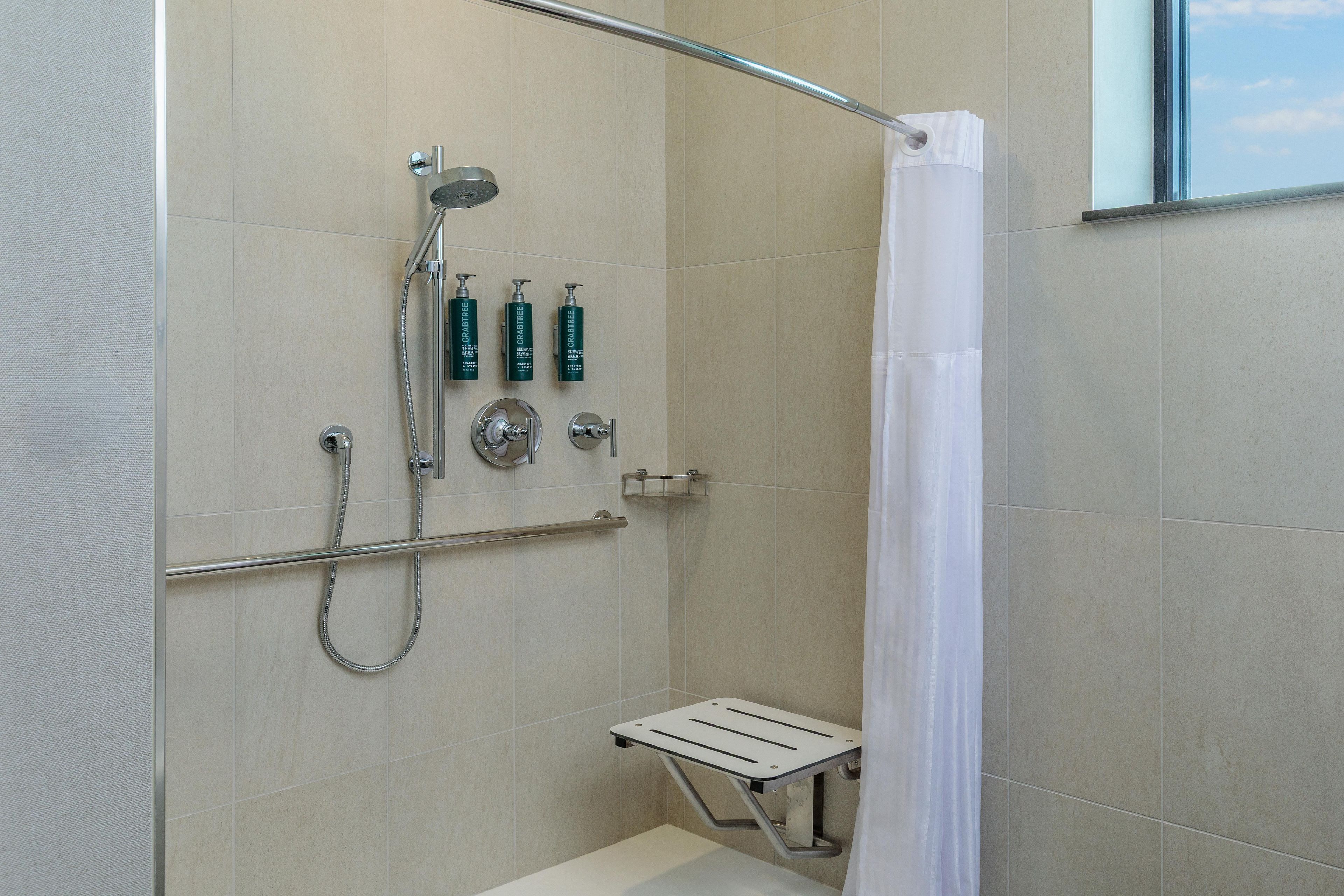 Zona de ducha con mampara de vidrio, barandilla y ducha.
