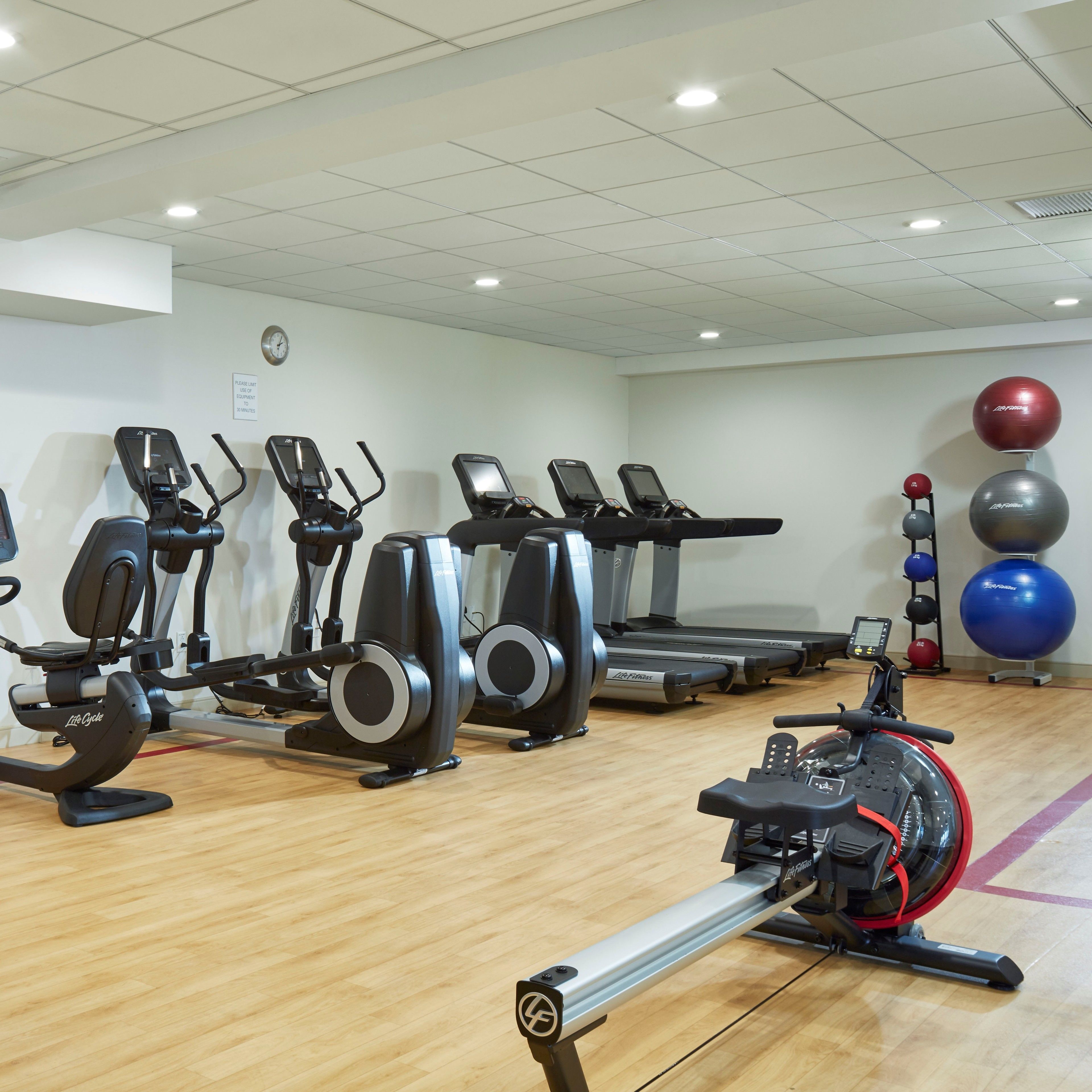 A gym with various exercise equipment including treadmills, elliptical machines, and stationary bikes.