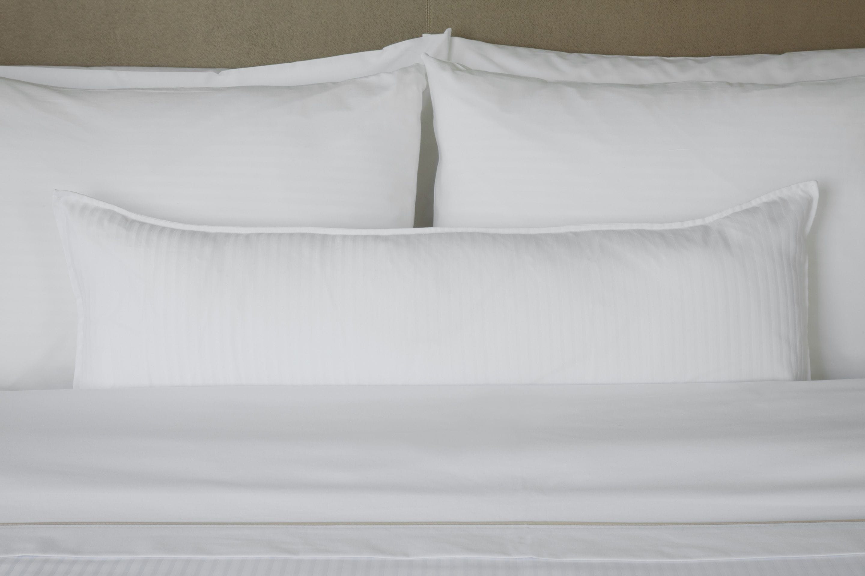Una cama bien hecha con sábanas y almohadas blancas.
