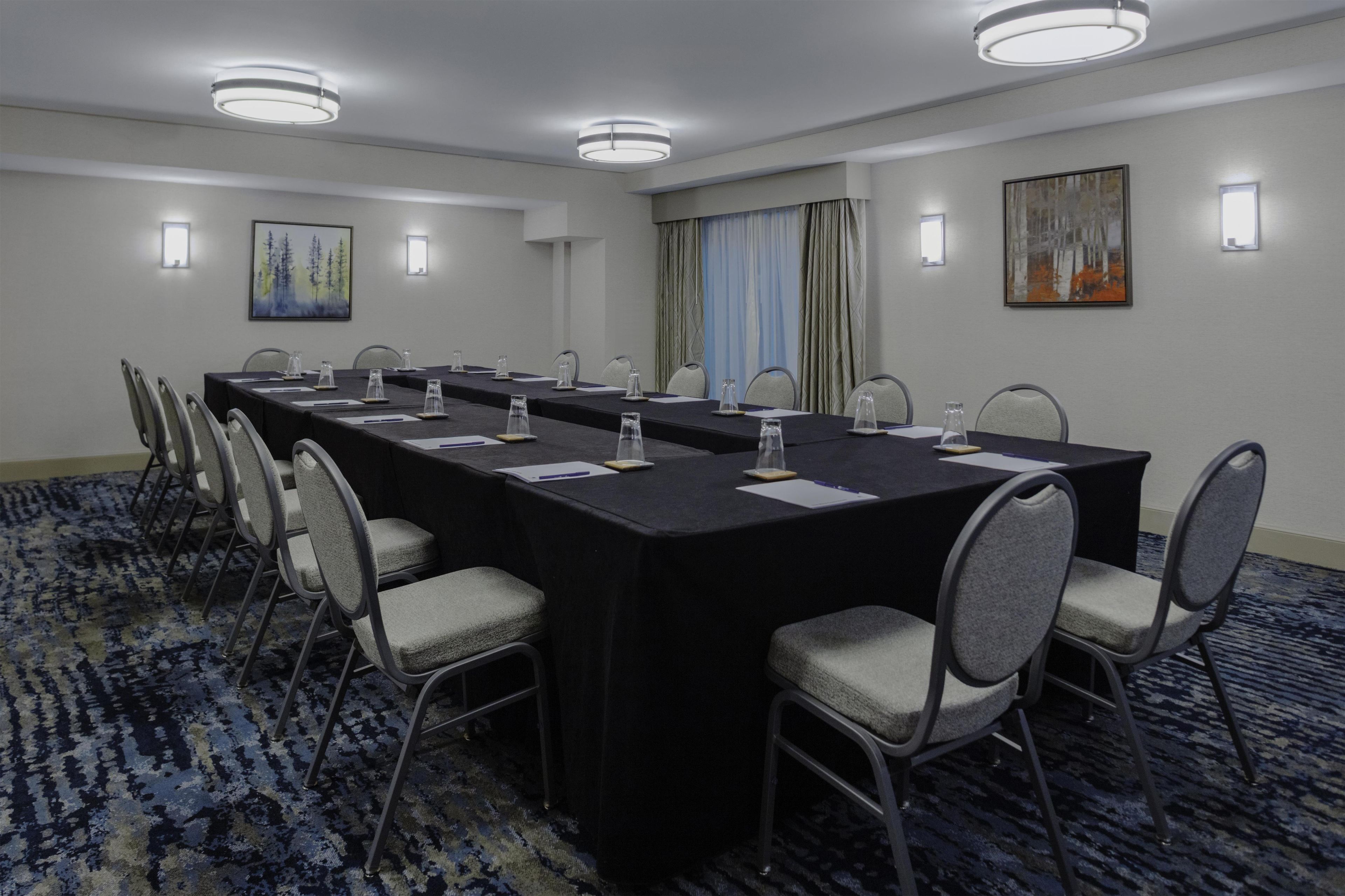 A conference room with a long table, chairs, and a carpeted floor.