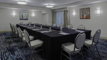 A conference room with a long table, chairs, and a carpeted floor.