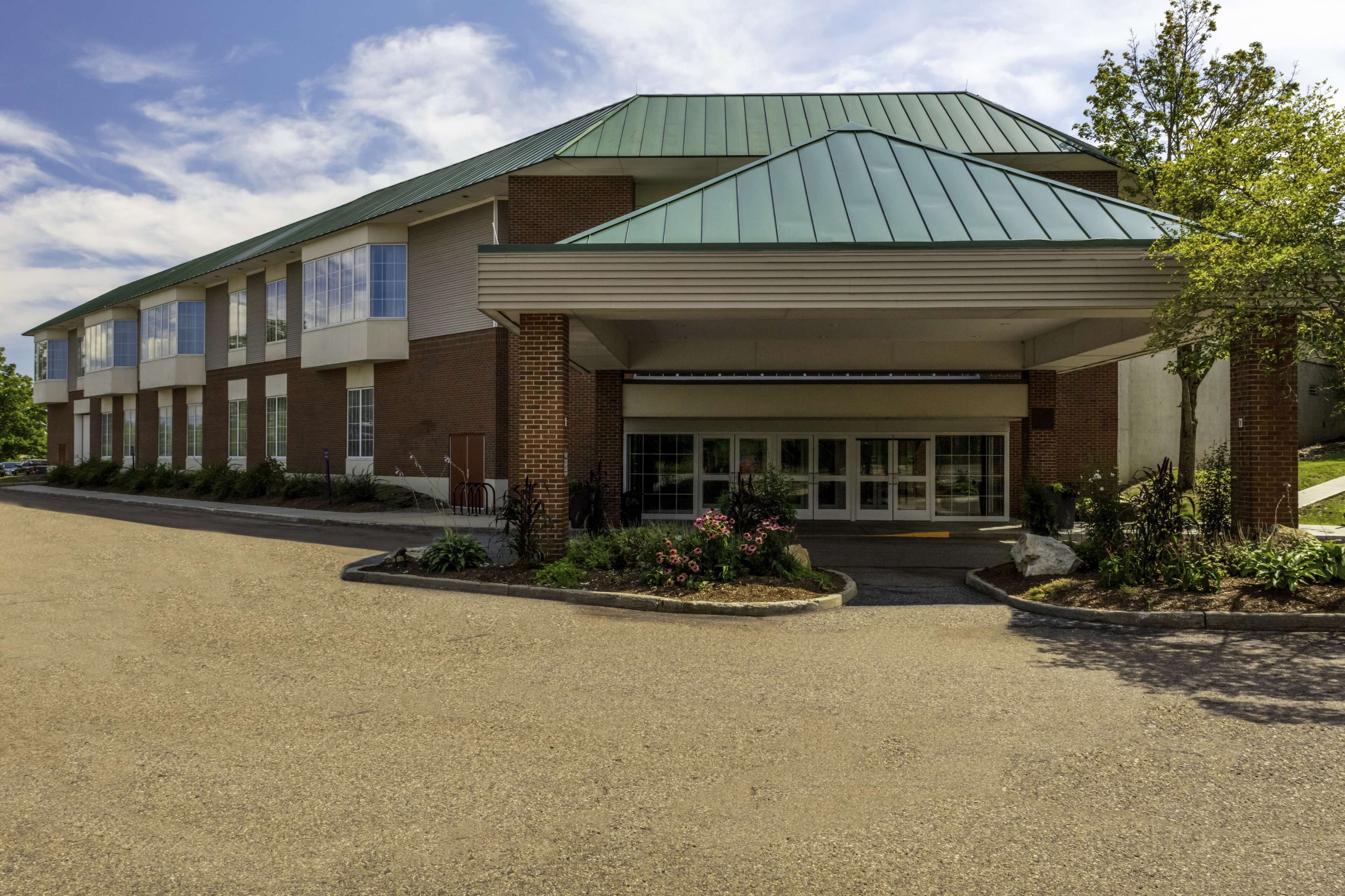 A modern building with a green roof, large windows, and a covered entrance.