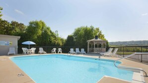 Una piscina con sillas de descanso y un pabellón.