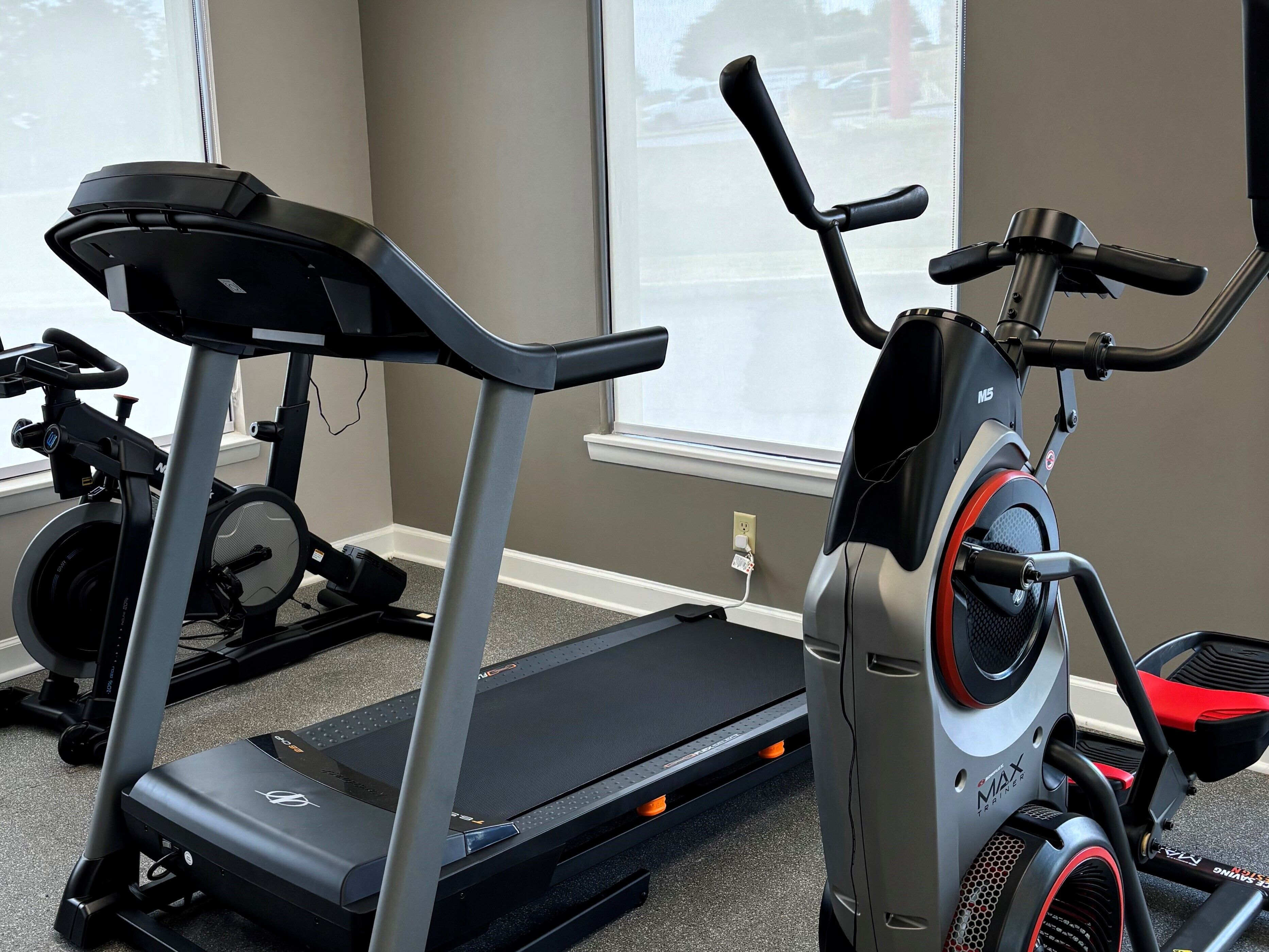 Une salle de sport équipée de tapis de course et de vélos d’appartement.