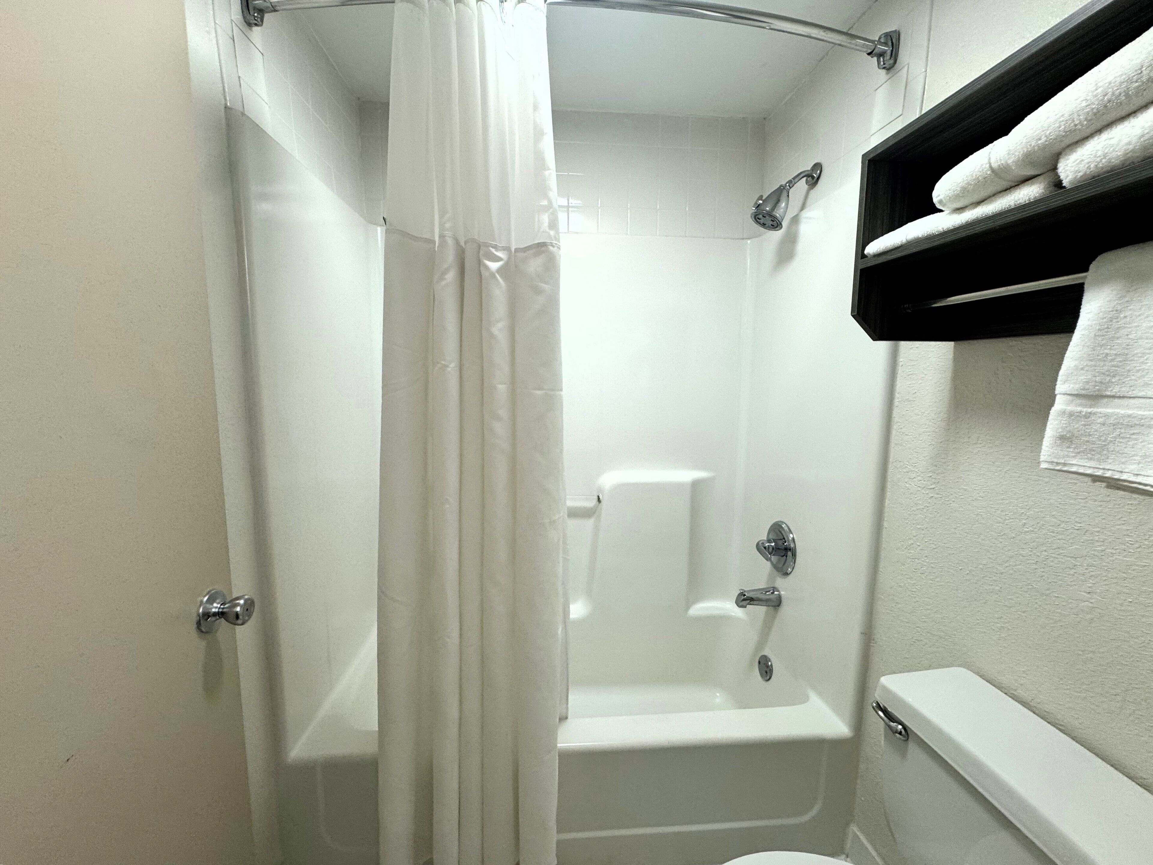 A bathroom with a shower, toilet, and towel rack.