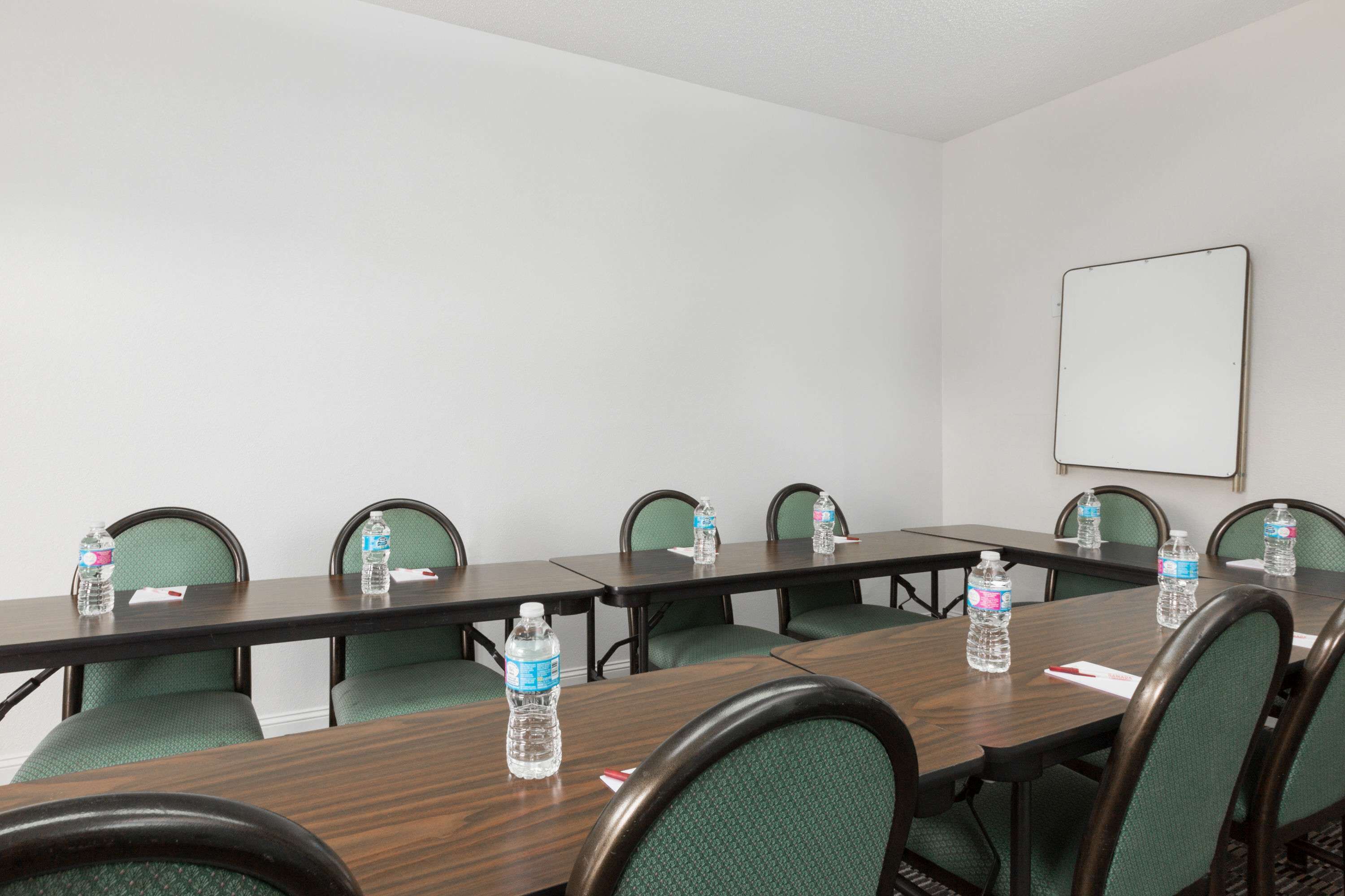 A conference room with a long table, green chairs, and water bottles on the table.