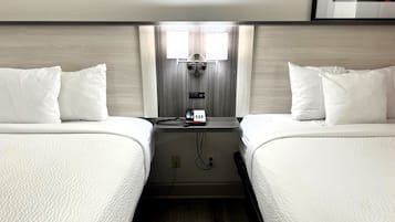 Camera d'albergo con due letti, un comodino con una lampada e un telefono a parete.