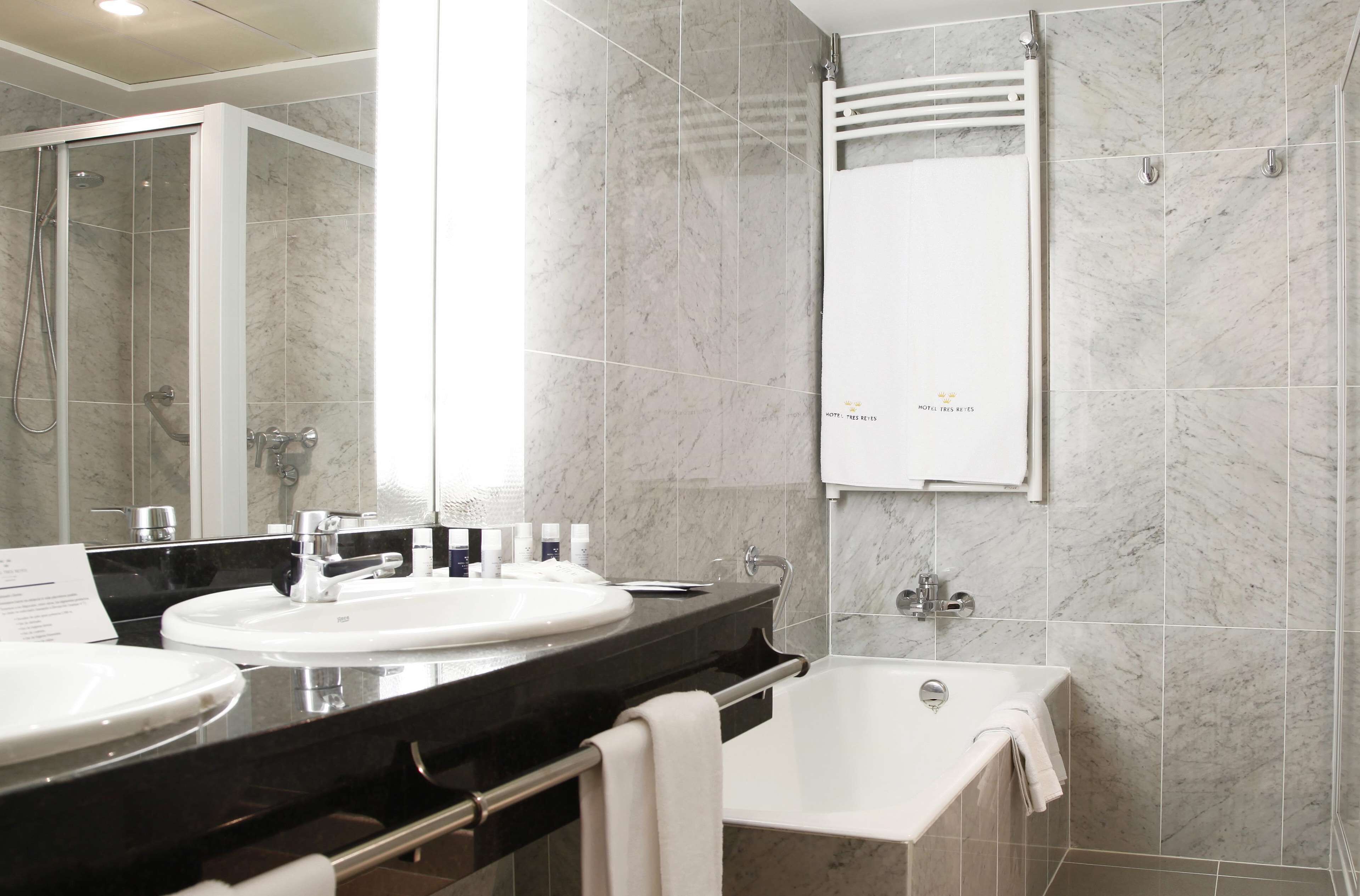 A modern bathroom with a double sink, a bathtub, and a walk-in shower.