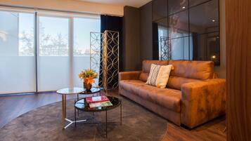A modern living room with a leather sofa, a glass coffee table, and a decorative metal partition.