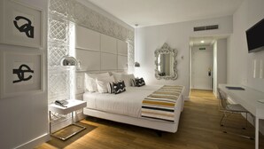 A modern hotel room with a large bed, a bedside table with a lamp, a mirror, and a desk with a chair. - Hotel Tres Reyes Pamplona (Pamplona)