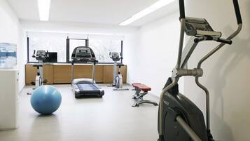 A gym with exercise equipment including a treadmill, elliptical, and stationary bike.