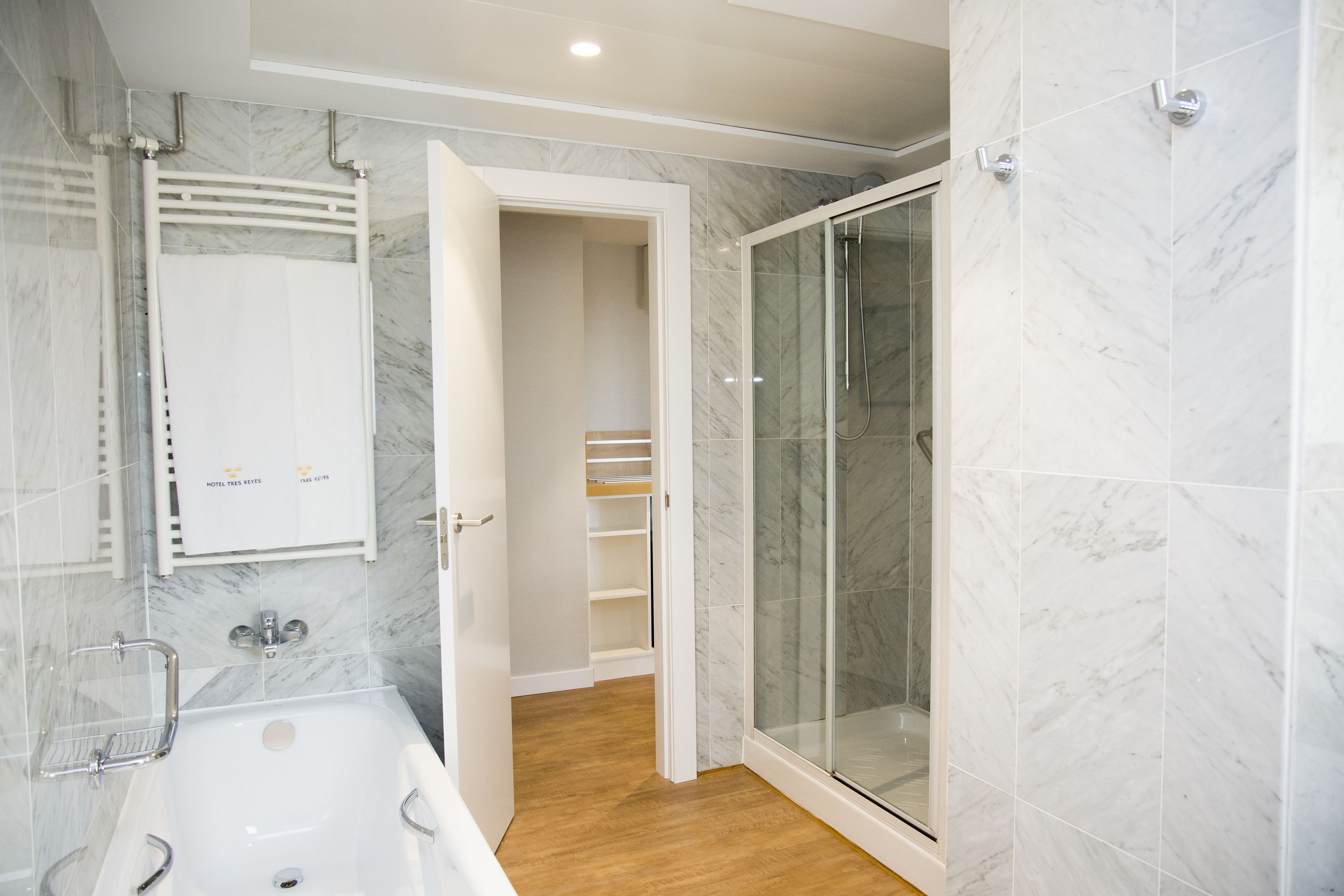 Un baño moderno con ducha de vidrio, una bañera blanca y un revestimiento de mármol.