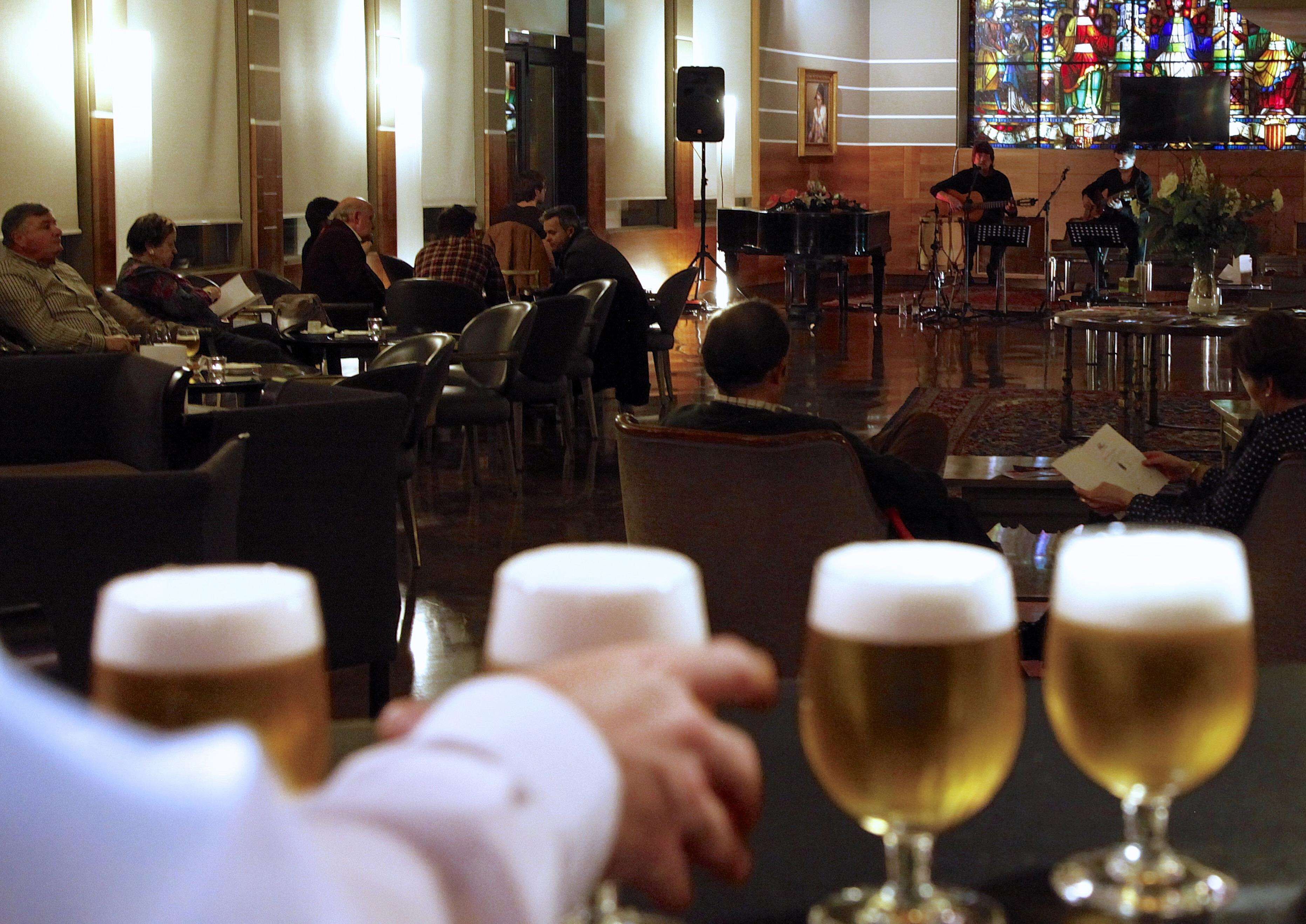 A hotel lobby with a piano, a band, and guests seated at tables.