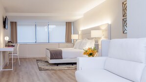 A modern hotel room with a bed, a sofa, a desk, and a TV. - Hotel Tres Reyes Pamplona (Pamplona)