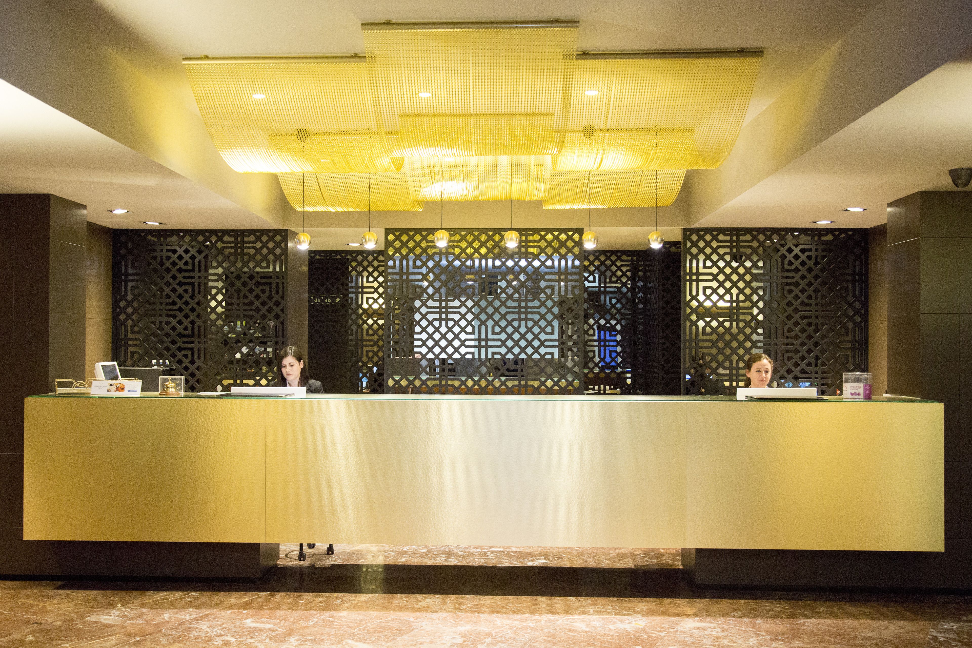 A reception desk with a modern design, featuring a central light fixture and decorative panels.
