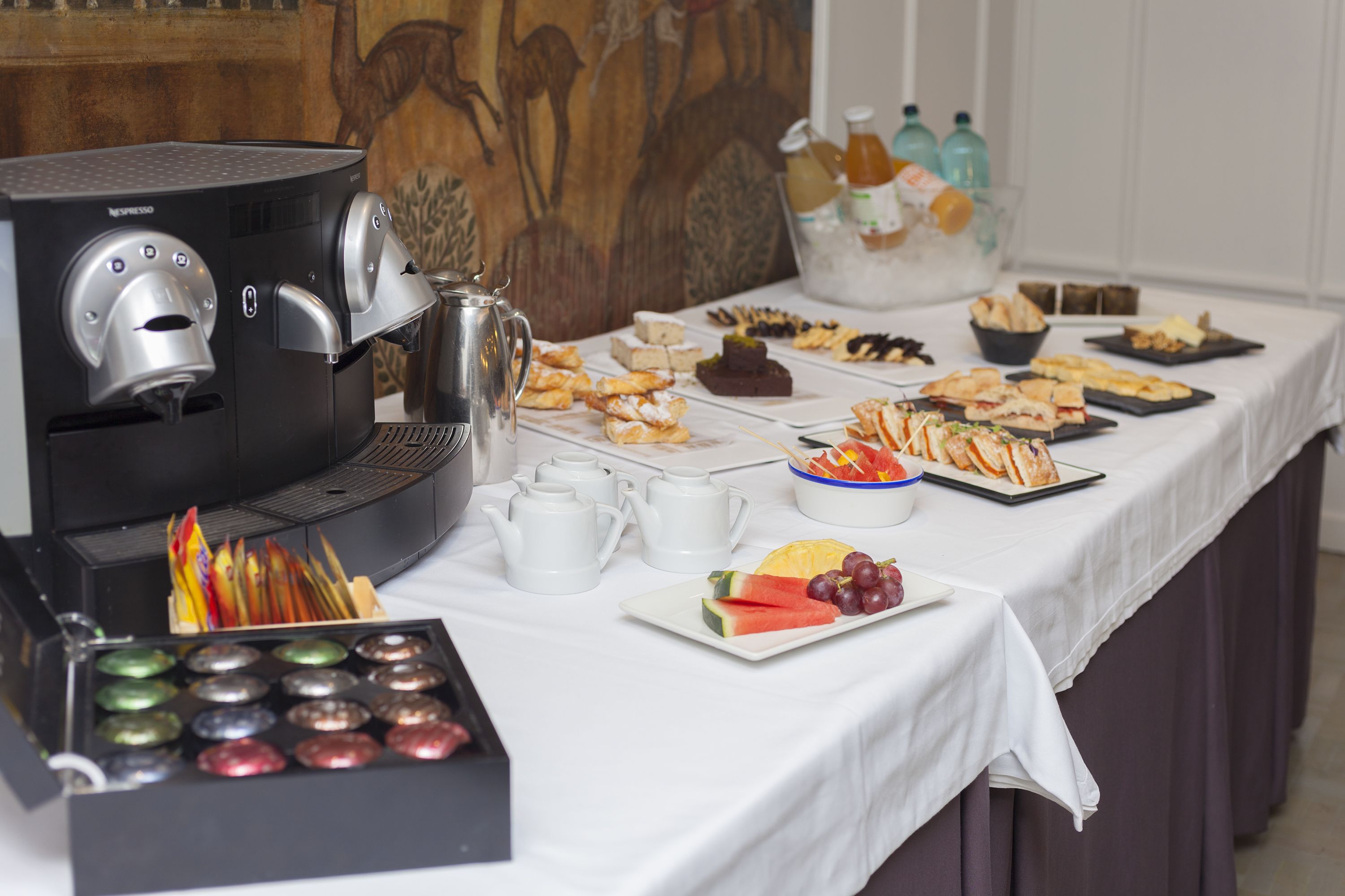 A buffet table with various food items, a coffee machine, and a fruit bowl.