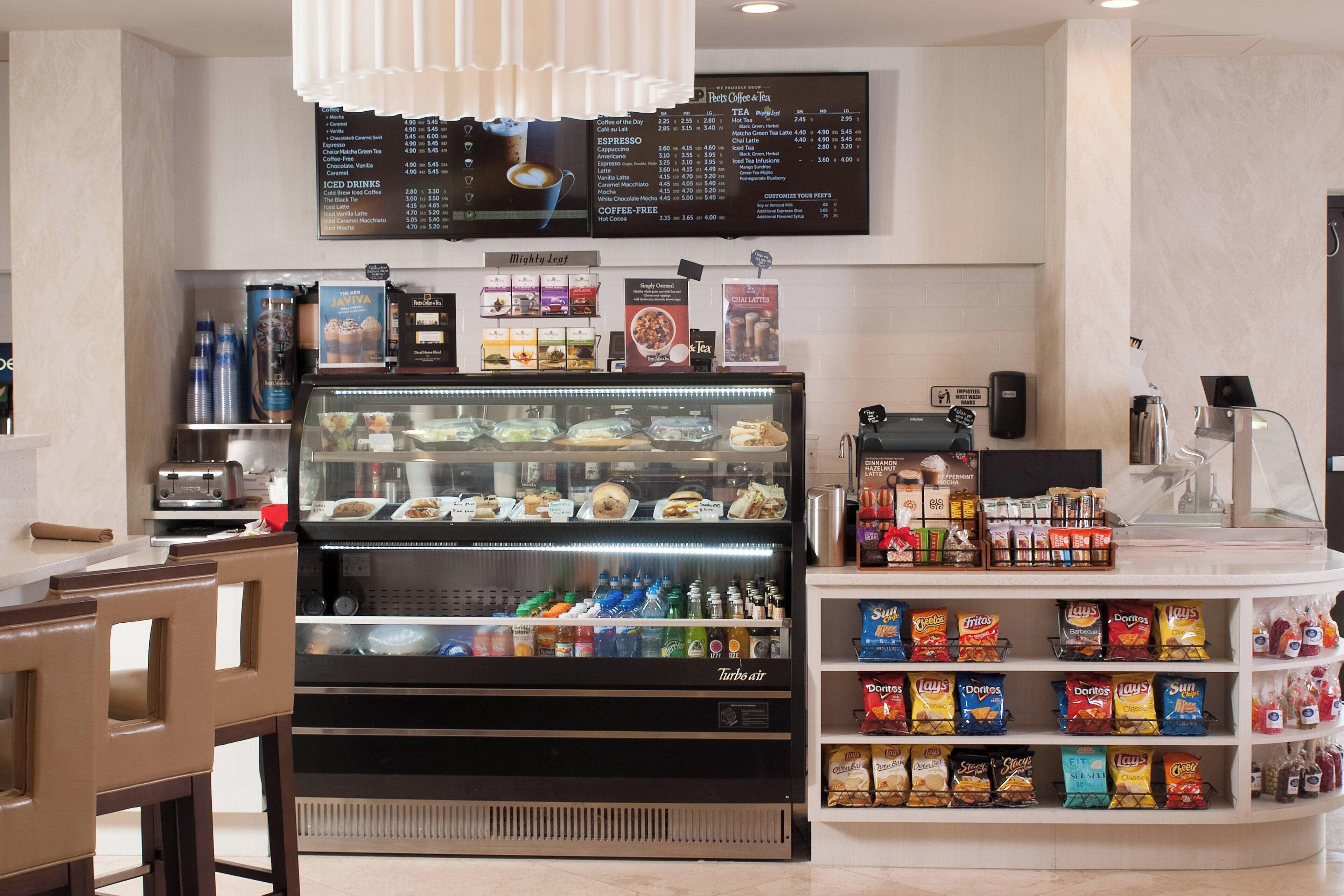 Un stand de restauration avec un tableau affichant le menu, une vitrine réfrigérée et une étagère pour les collations.