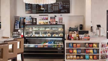 Quiosque de comida com um painel de cardápio, um refrigerador e uma prateleira para lanches.