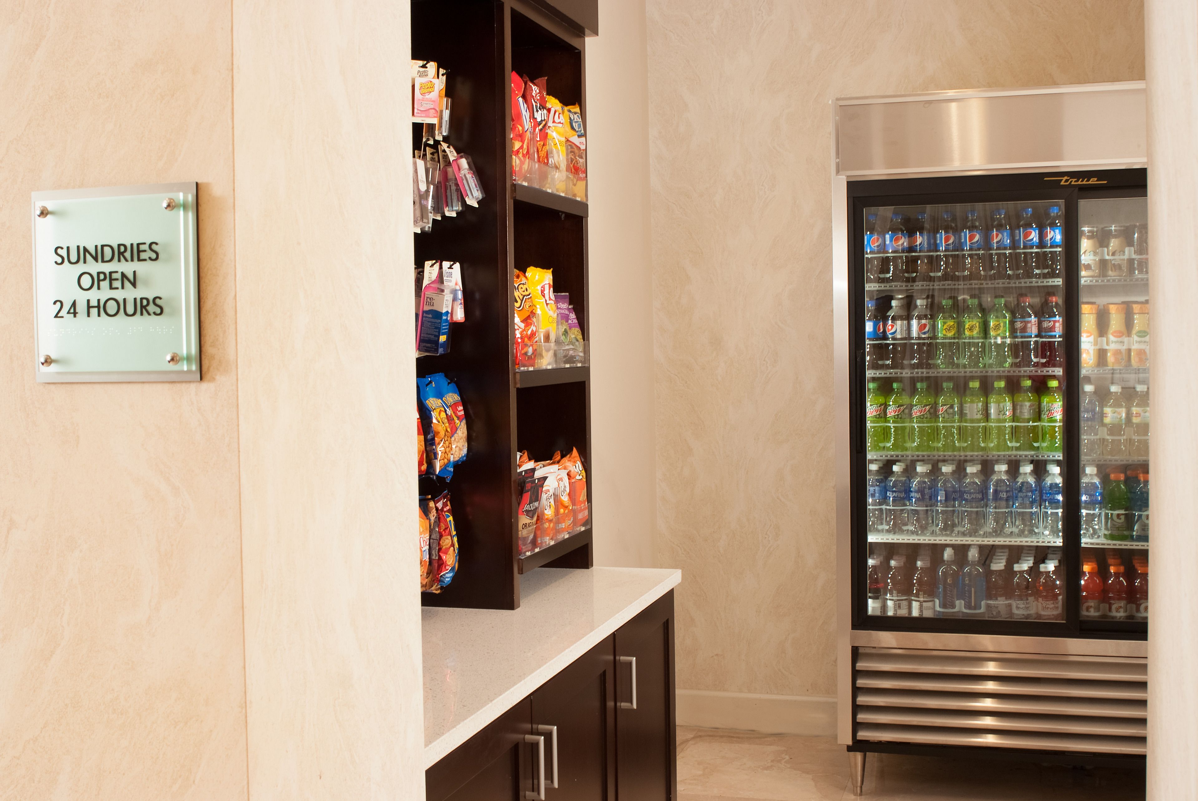 Een automaat gevuld met snacks en een koelkast met water en frisdranken.
