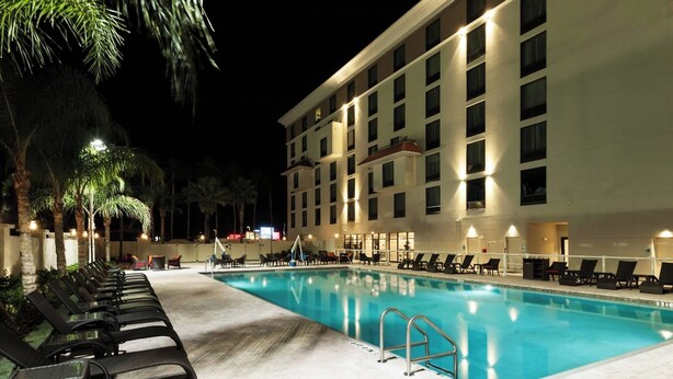 A swimming pool with lounge chairs and a building with multiple floors and balconies.