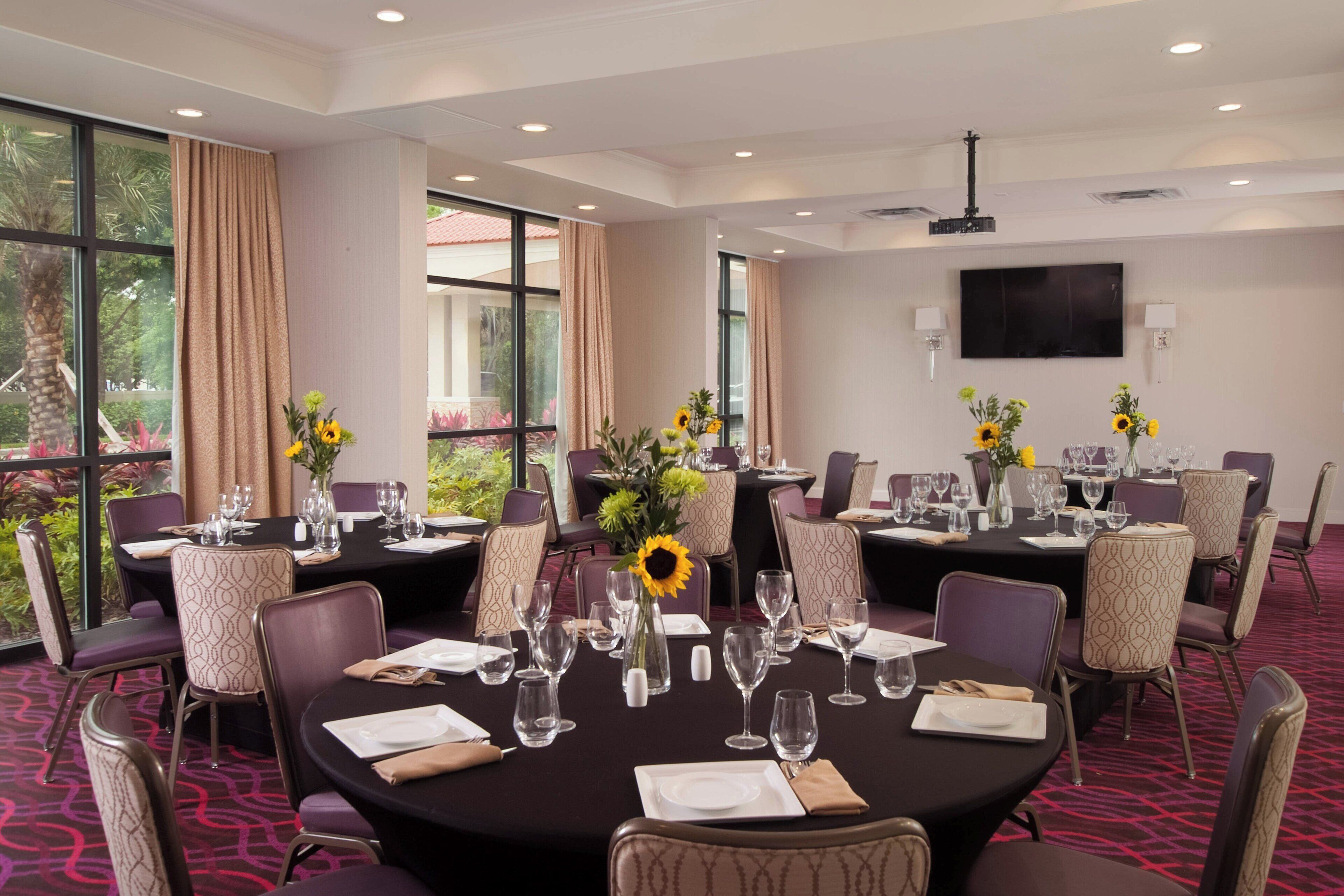 Un salón de conferencias con mesas redondas, sillas y girasoles.