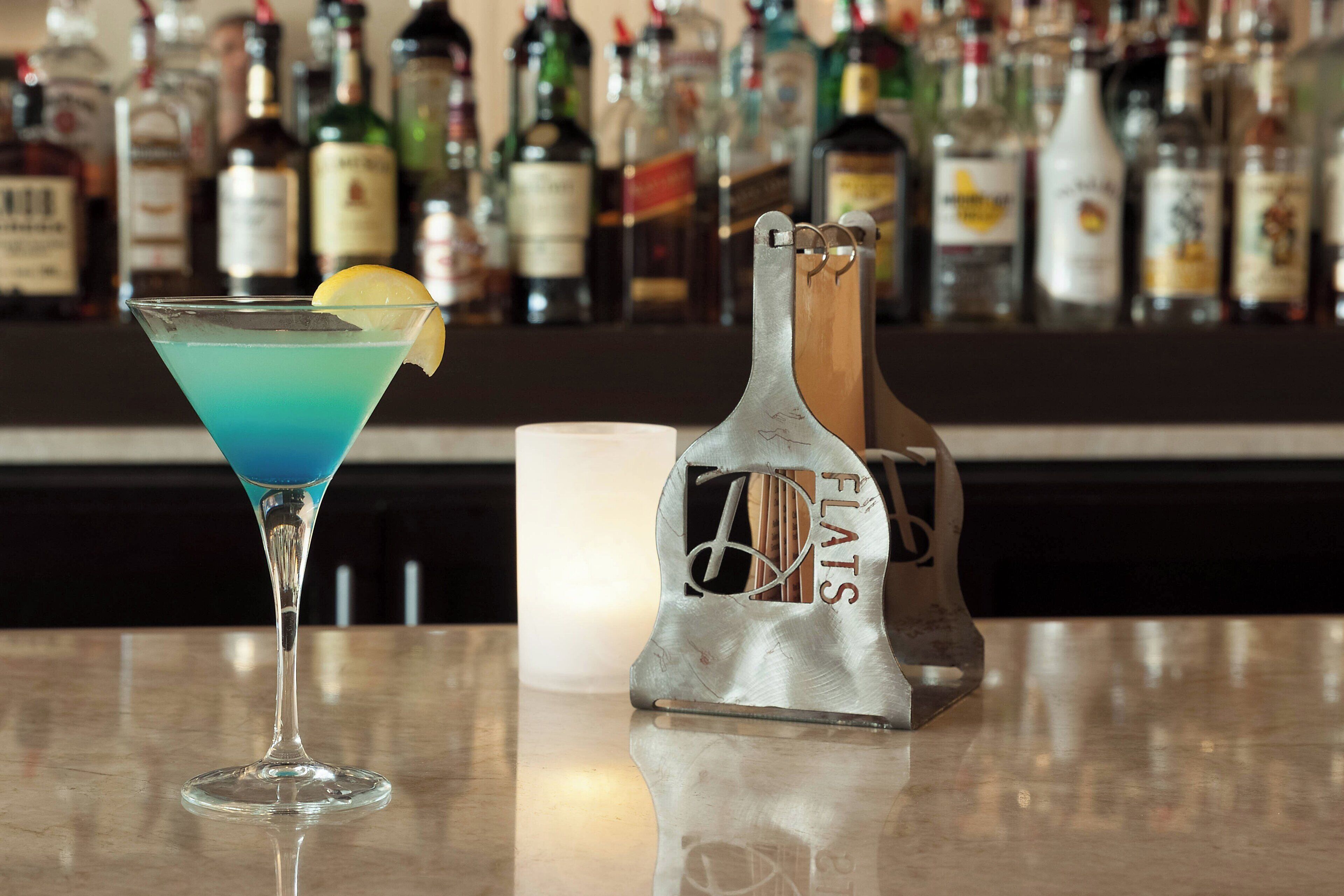 A bar with a blue cocktail and a bottle of FLATS vodka.