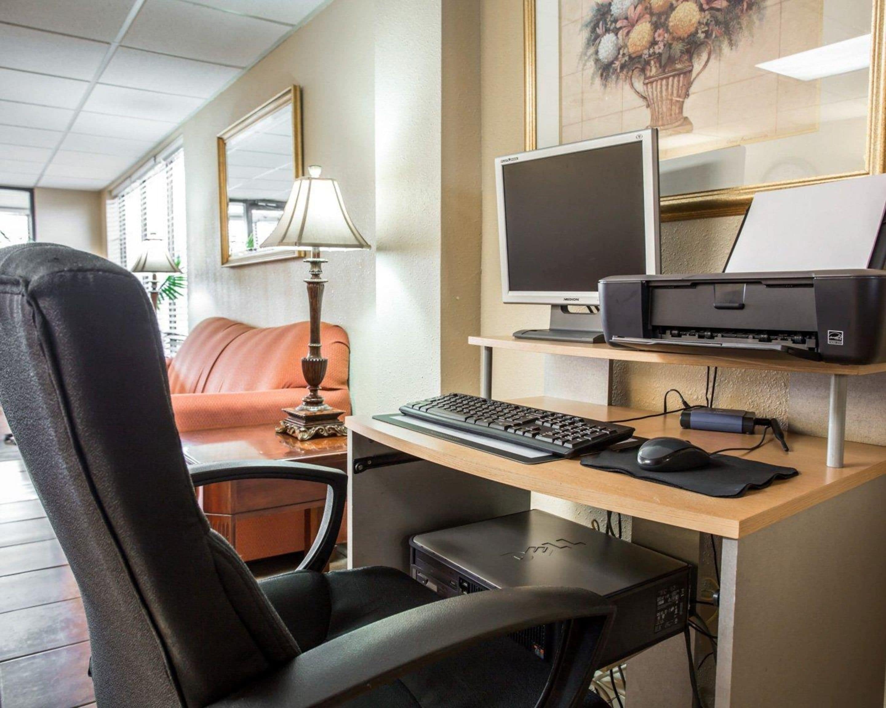 A home office setup with a desk, computer, printer, and a black office chair.