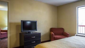 A hotel room with a bed, a television on a dresser, a chair, and a window.