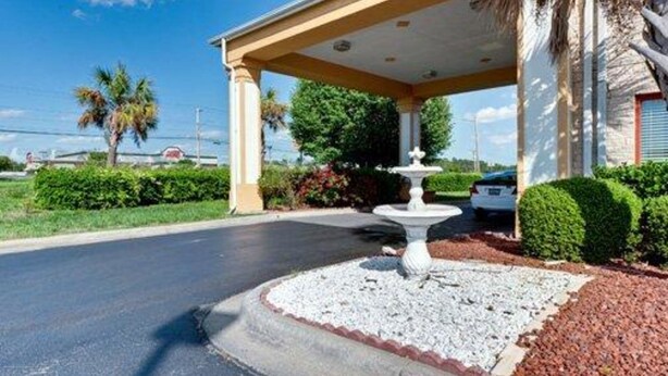 A covered entrance with a fountain, palm trees, and a car parked nearby. - Quality Inn & Suites Monroe (Monroe)