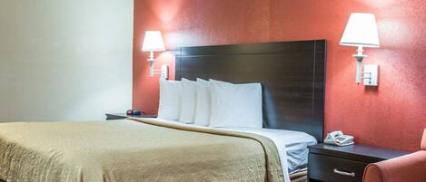 A hotel room with a large bed, two bedside tables, a nightstand, a chair, and two wall-mounted lamps.
