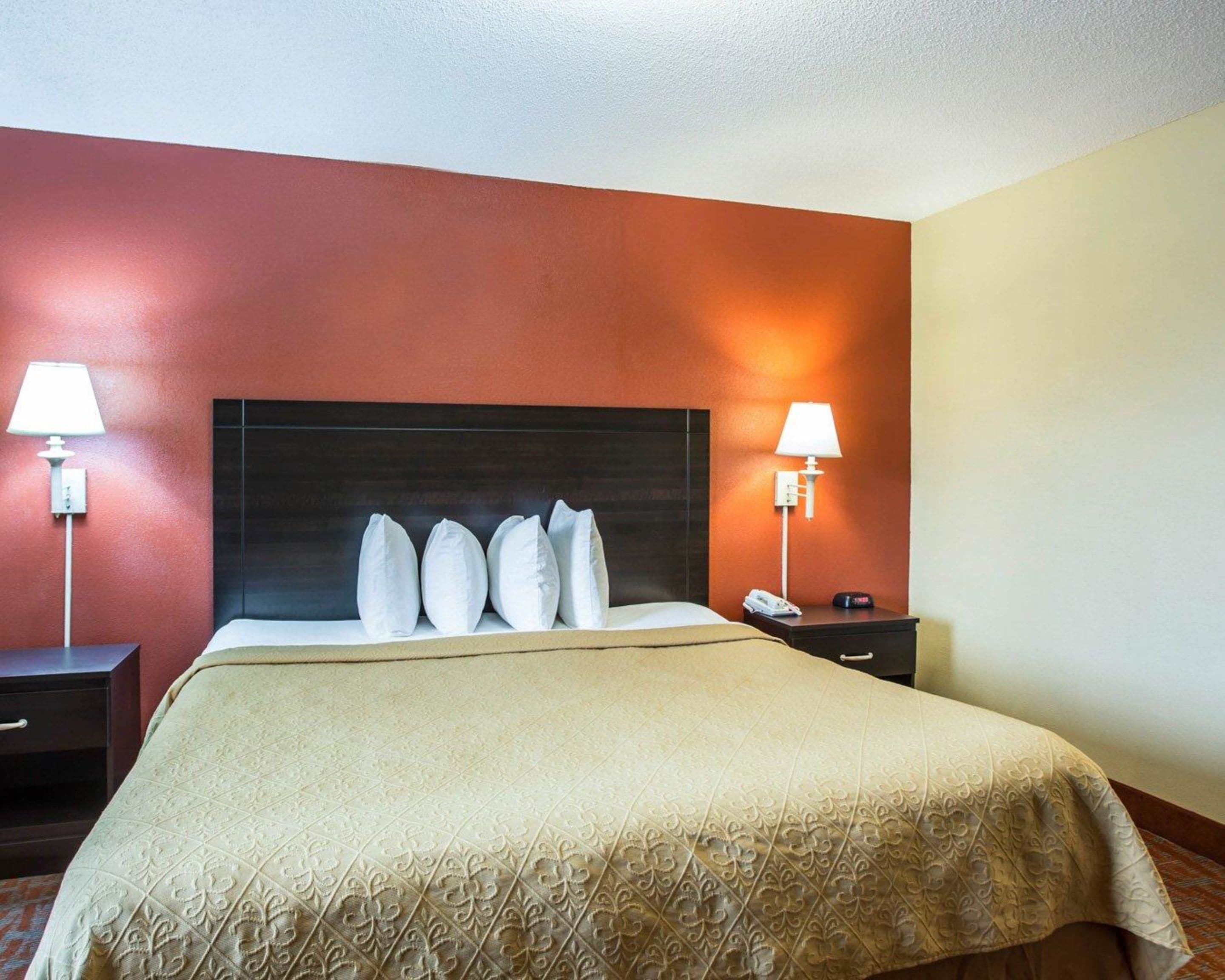 Habitación de hotel con una cama grande, dos mesitas de noche y un cabecero.