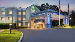 Et Holiday Inn Express & Suites hotel med moderne design, der har en overdækket indgang og amerikanske flag.