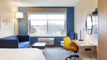 Une chambre d’hôtel équipée d’un lit, d’un bureau, d’une chaise, d’une fenêtre avec vue et d’un téléviseur fixé au mur.