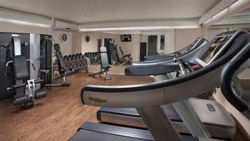 A gym with treadmills, weight machines, and dumbbells.