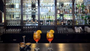 A bar area with shelves of glasses and bottles, two glasses with orange slices on the counter. - The Dan Carmel Hotel (Haifa)