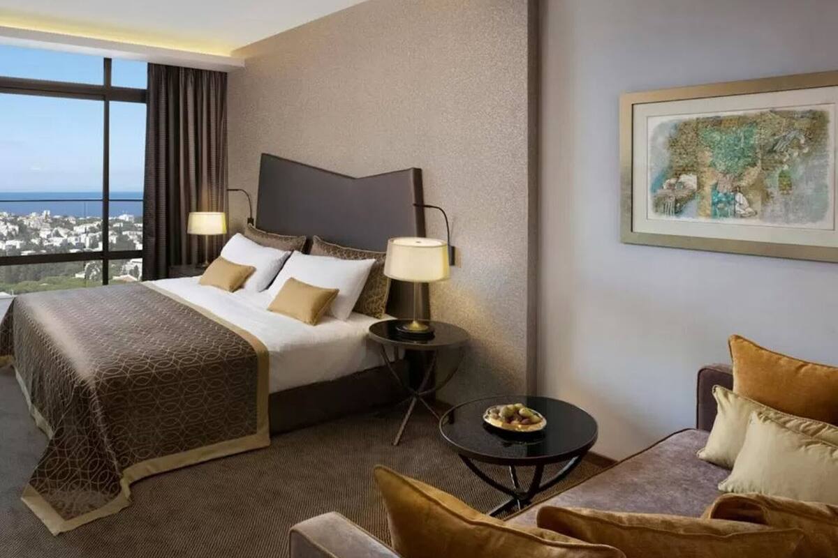 A hotel room with a large bed, two bedside tables with lamps, a small round table with a plate, and a framed map on the wall.