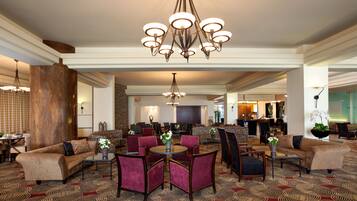 A spacious lobby with a large chandelier, multiple seating areas, and a patterned carpet.