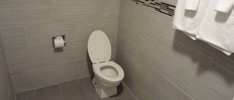A small, clean bathroom with a toilet, a towel rack, and a toilet paper holder.