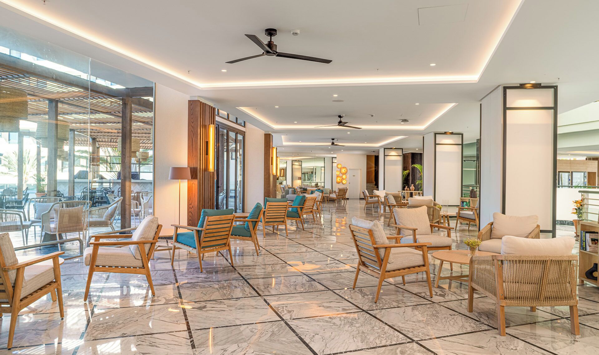Un hall amplio con mobiliario moderno, suelo de mármol y ventiladores de techo.