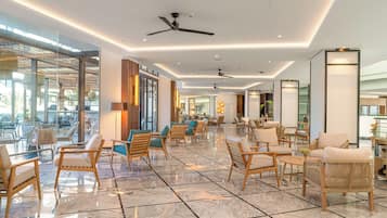 Un hall amplio con mobiliario moderno, suelo de mármol y ventiladores de techo.