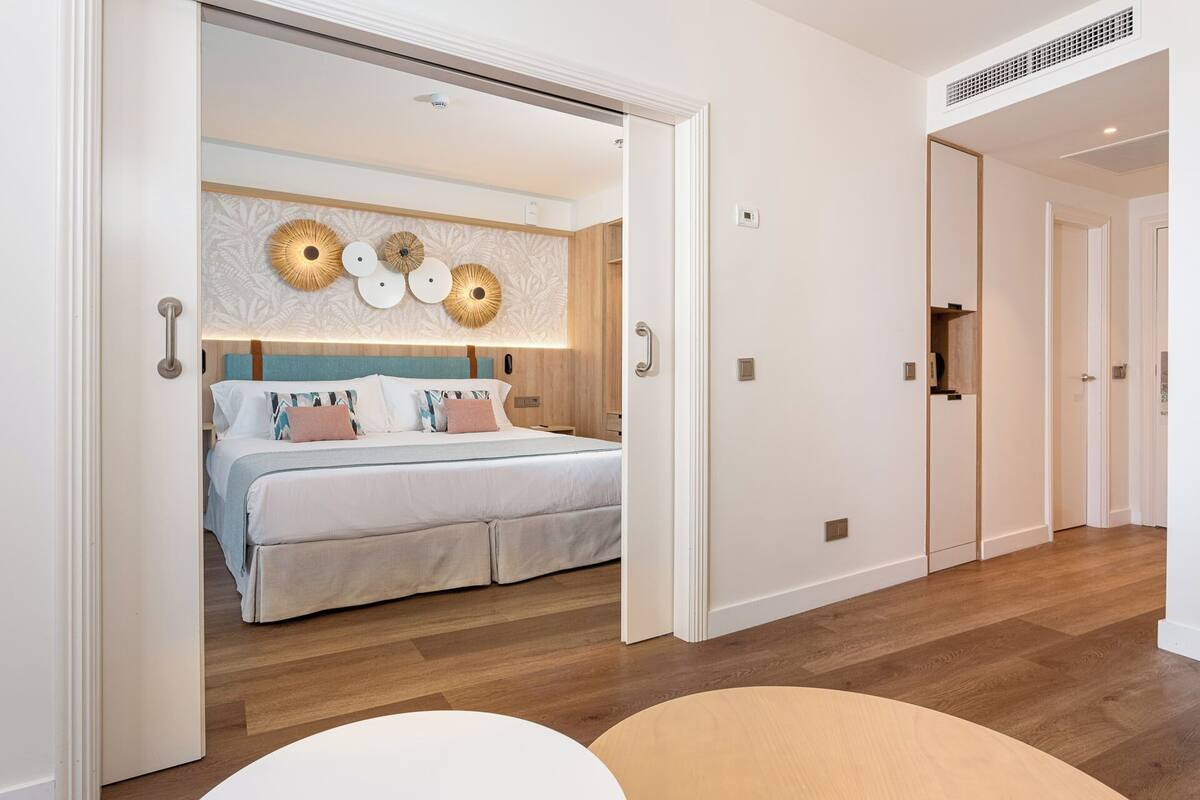 A modern hotel room with a large bed, a wooden floor, and a decorative wall with circular patterns.