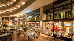 A modern restaurant with multiple dining areas, including a bar and a seating area with a view of the city.